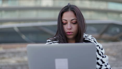 Thoughtful-young-woman-with-laptop-outdoor